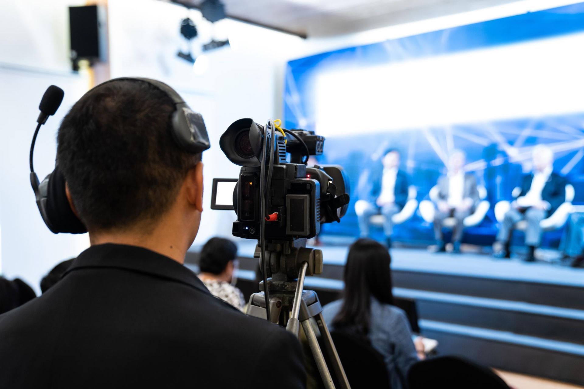 A man is holding a camera in front of a group of people.