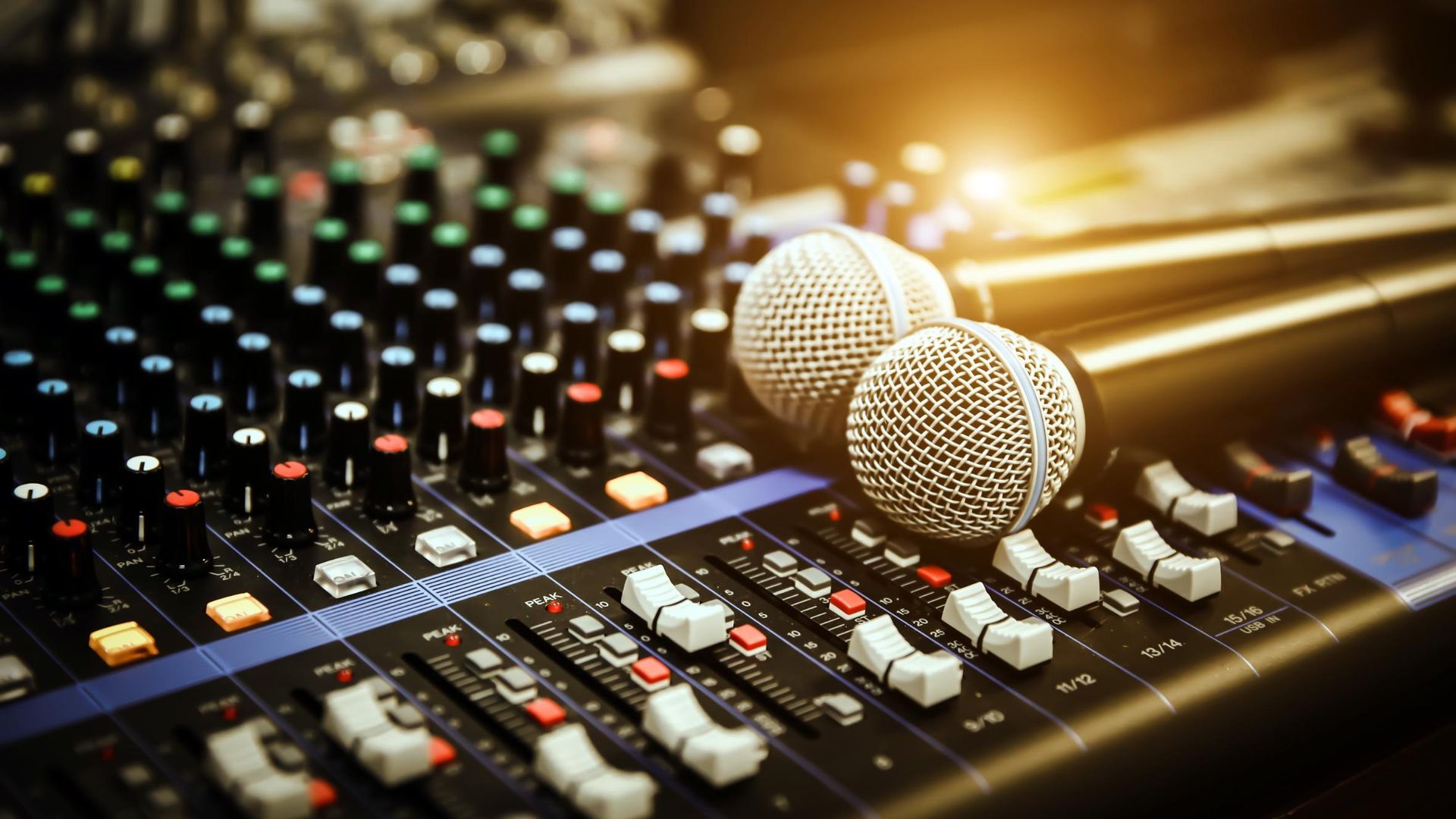 Two microphones are sitting on top of a mixer.