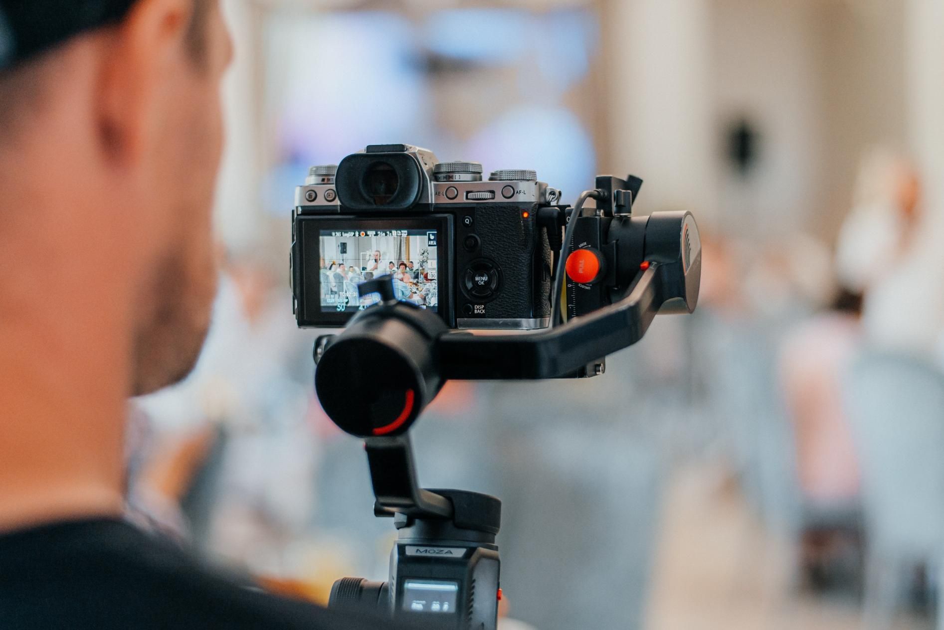 A man is holding a camera on a tripod.