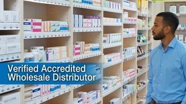 A man is standing in front of a row of shelves in a pharmacy.