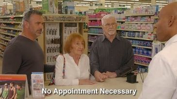 A group of people are sitting at a counter in a pharmacy talking to a pharmacist.