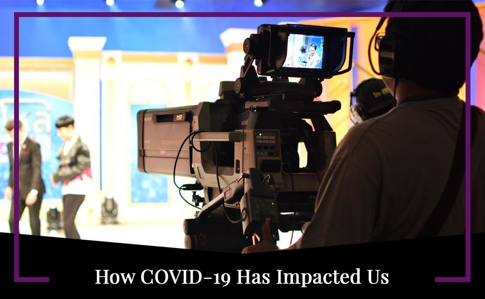 A man is holding a camera in front of a screen that says how covid-19 has impacted us.