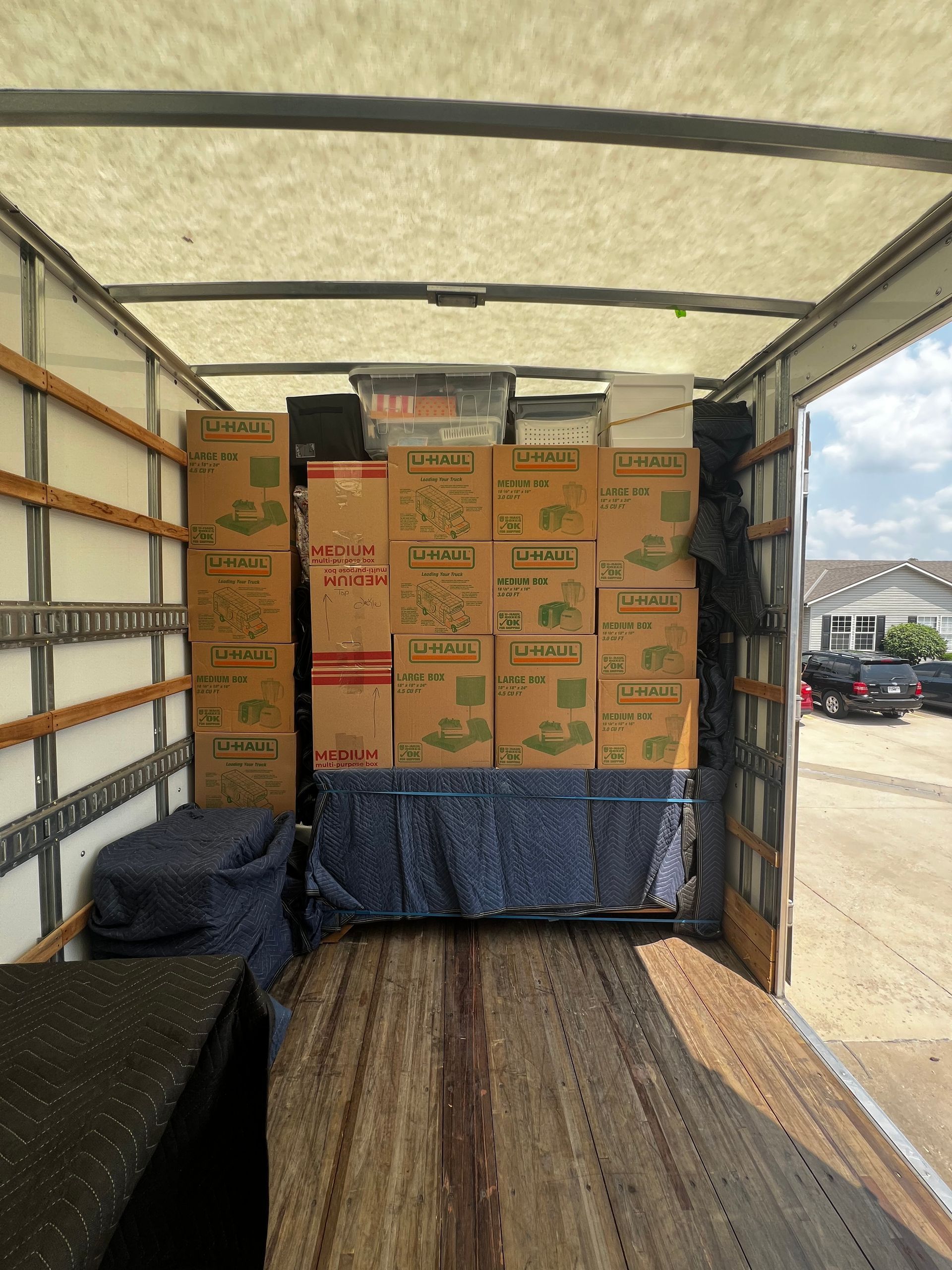 Boxes and furniture fill a moving truck, view from the open back.