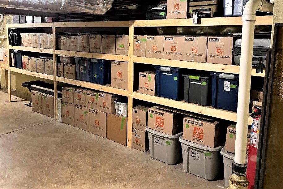 Wooden shelves stacked with boxes and bins in a basement.
