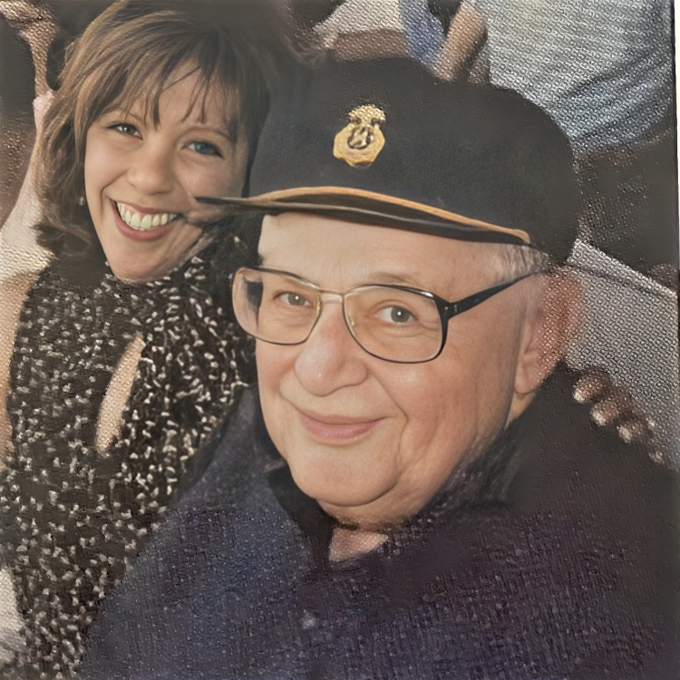 Smiling woman with shoulder-length hair, and older man wearing glasses and a cap, smiling.