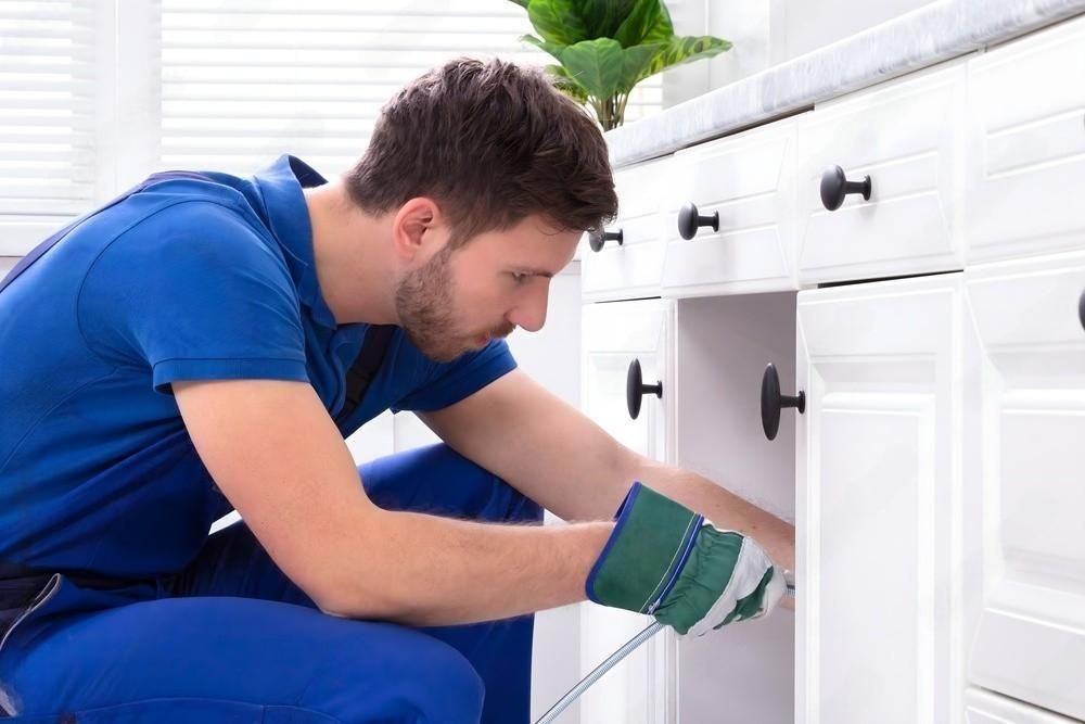 a man is fixing a sink in a kitchen .