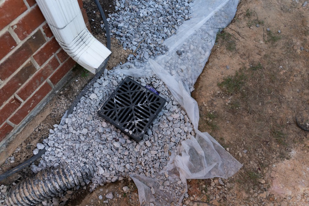 a drain is sitting in the dirt next to a brick wall .