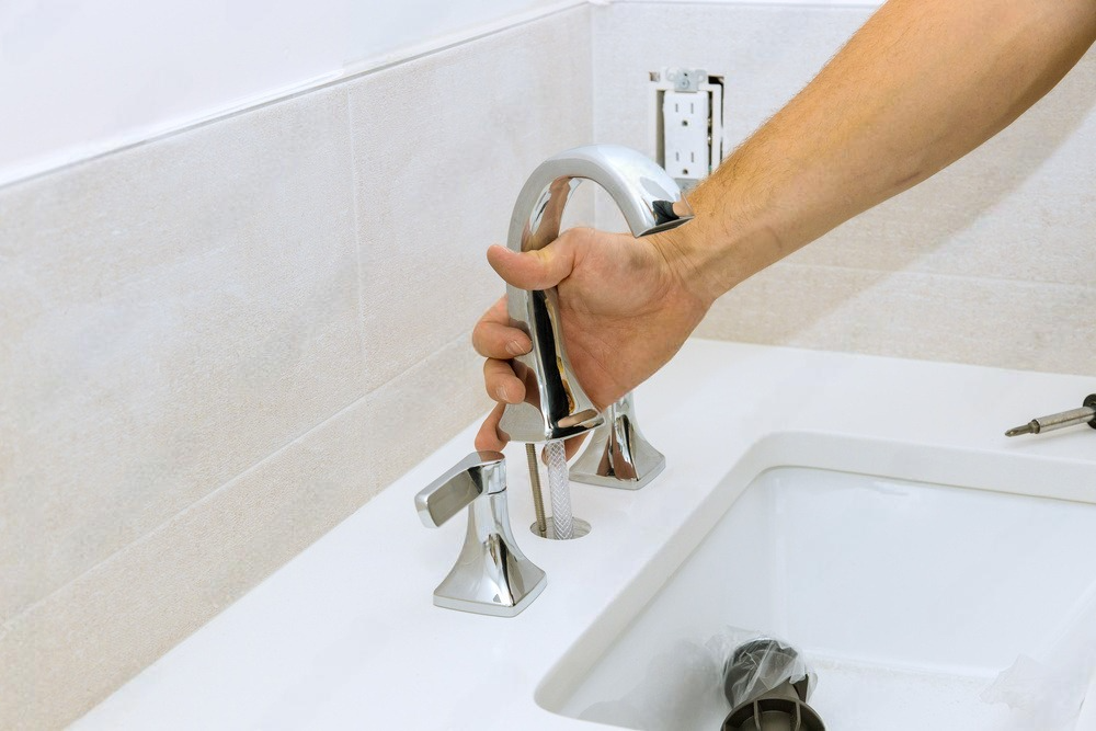 a person is holding a faucet over a bathroom sink .