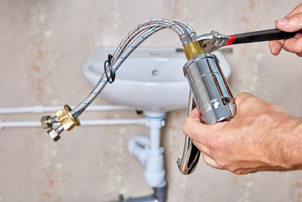 a person is fixing a sink faucet with a pair of pliers .