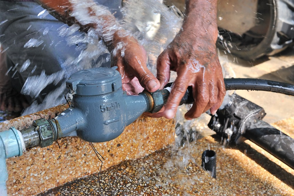 a person is fixing a water meter with water coming out of it