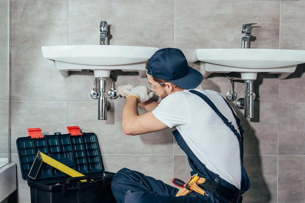 a plumber is fixing a sink in a bathroom .