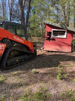 A bulldozer is parked next to a red shed.