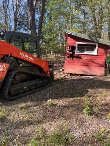 A bulldozer is parked next to a red shed.