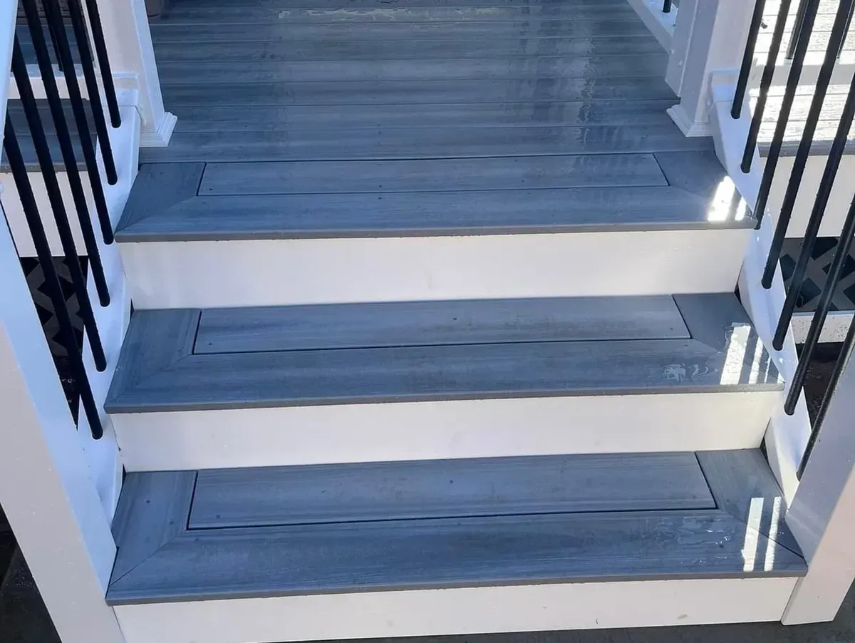A close up of a set of stairs with a black railing.