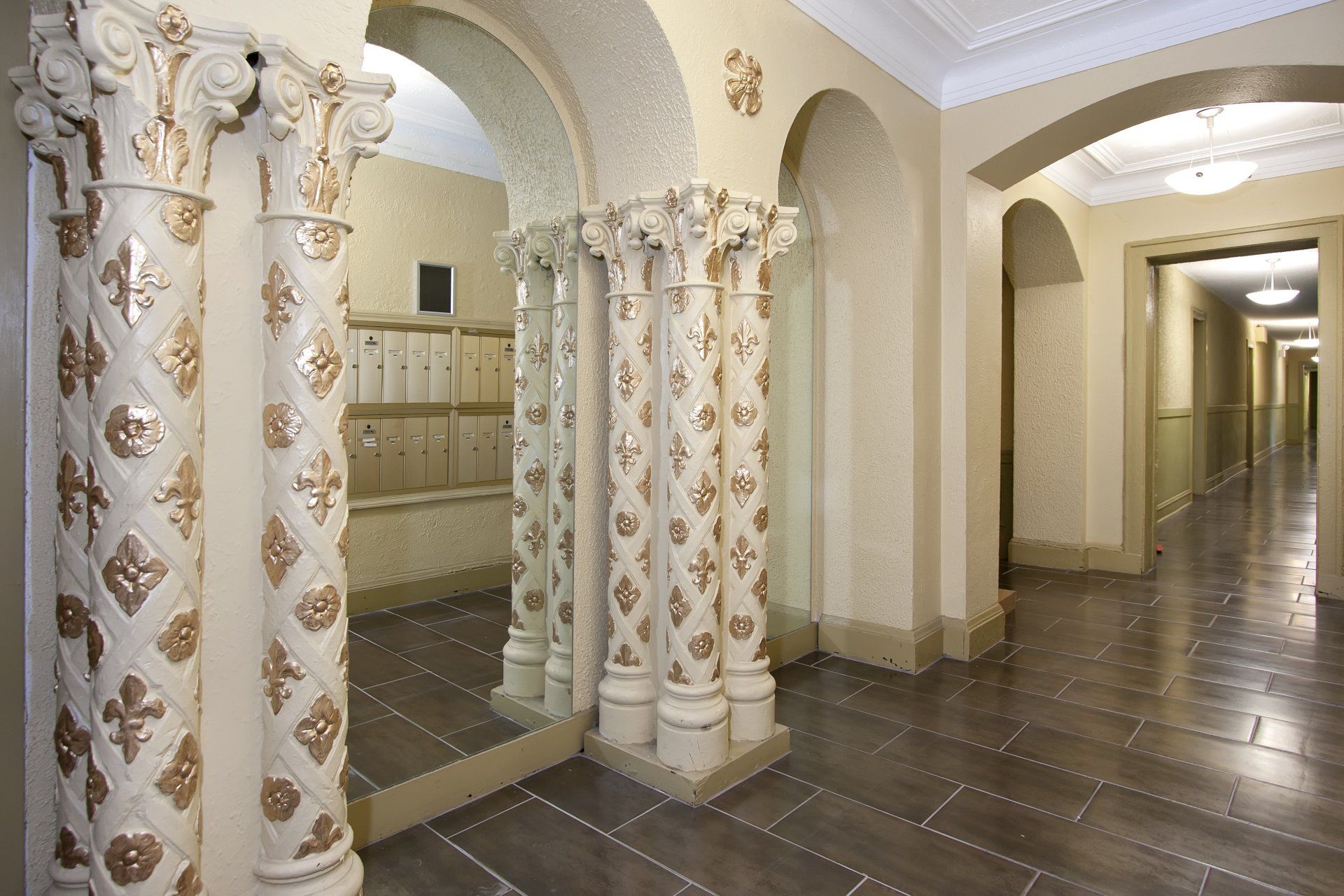 A hallway with columns and arches and a mirror
