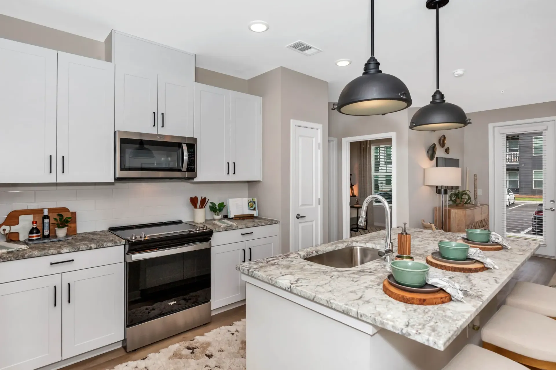 Modern white kitchen with marble island, stainless appliances, and bar seating.
