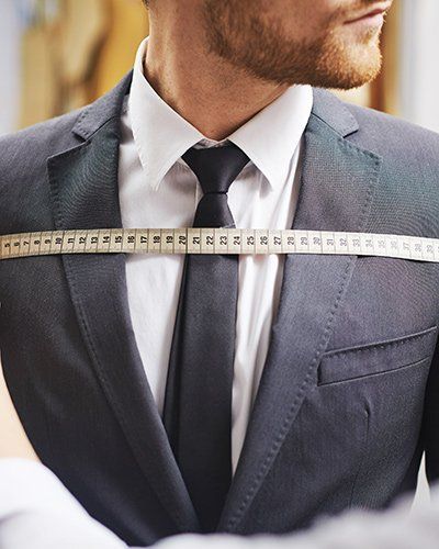 man in suit getting his chest measured