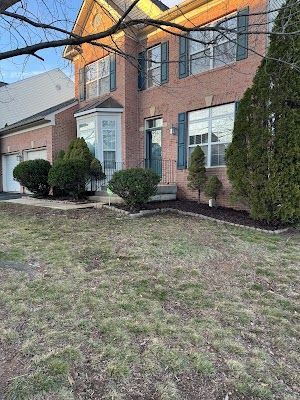 A large brick house with a large lawn in front of it.