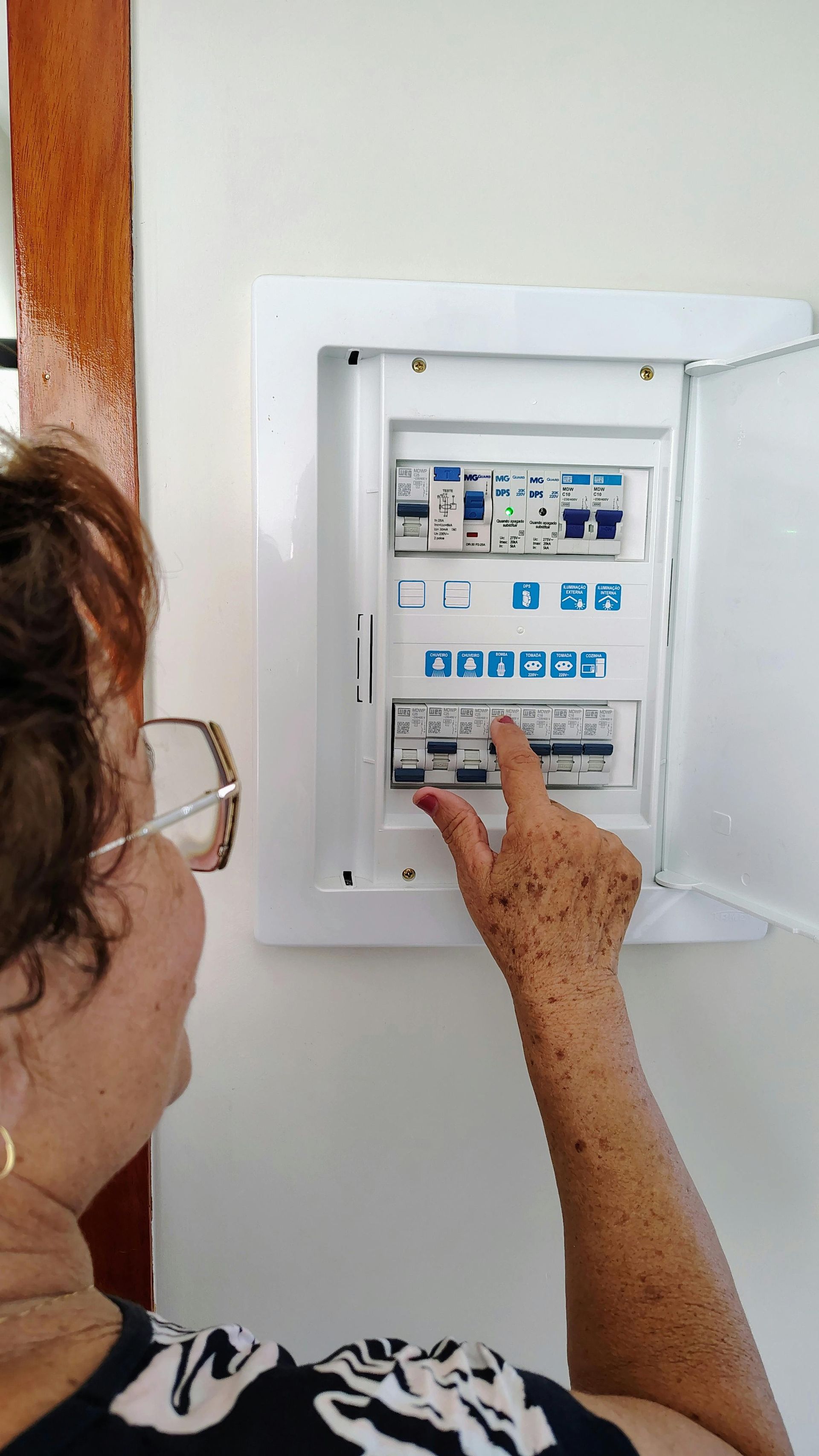 Person adjusting controls on a white wall-mounted electrical panel.