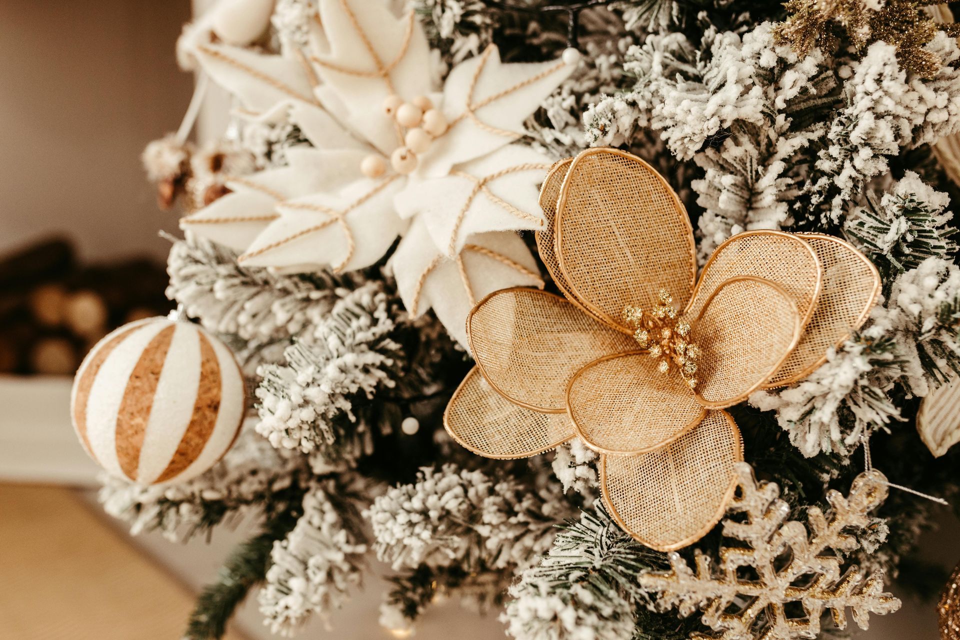 A festive, flocked Christmas tree decorated with white poinsettias, gold mesh flowers, striped ornaments, and snowflakes.