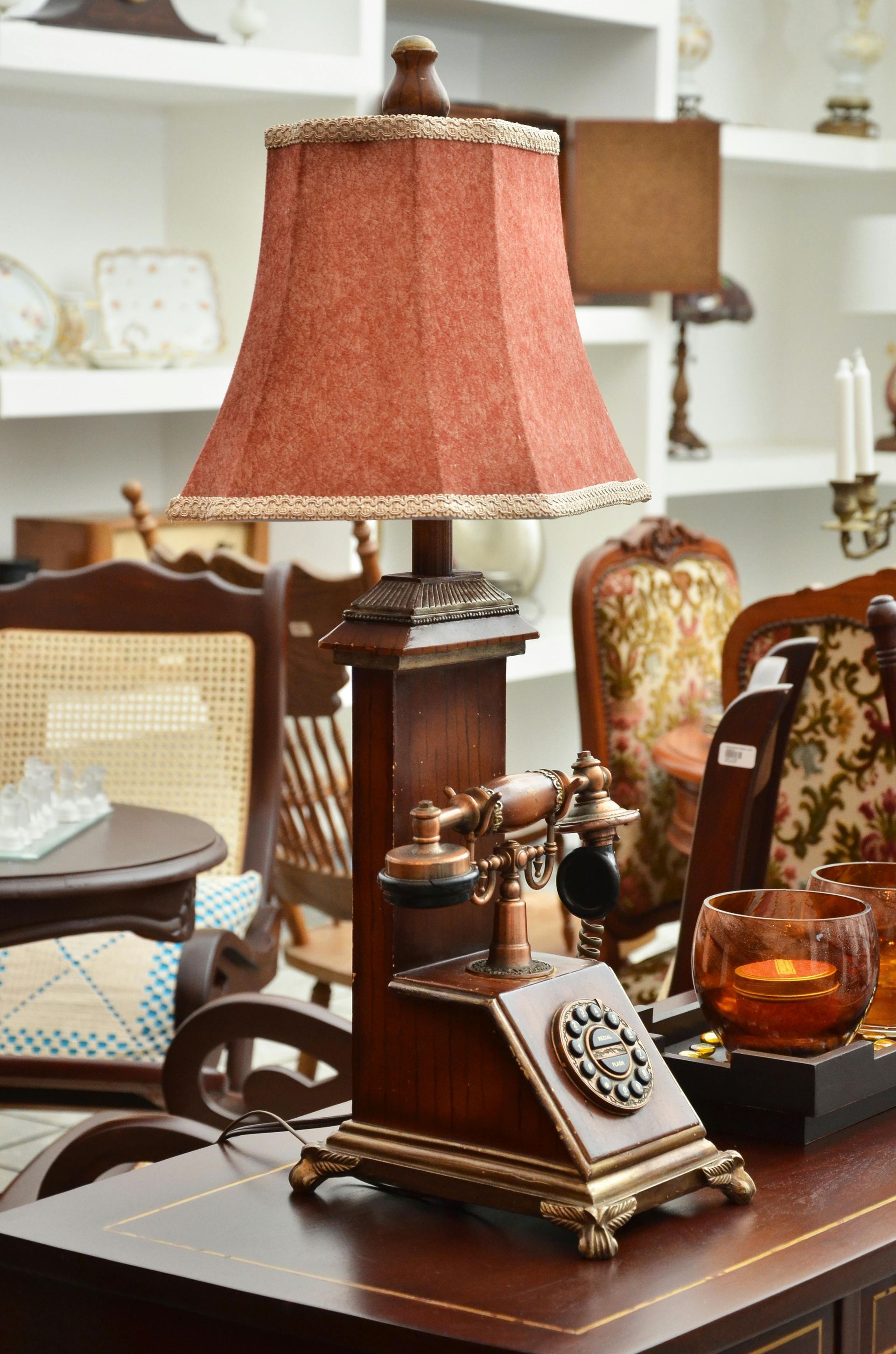 A vintage-style telephone lamp with a dark wood base, gold accents, and a textured, rust-colored fabric shade.