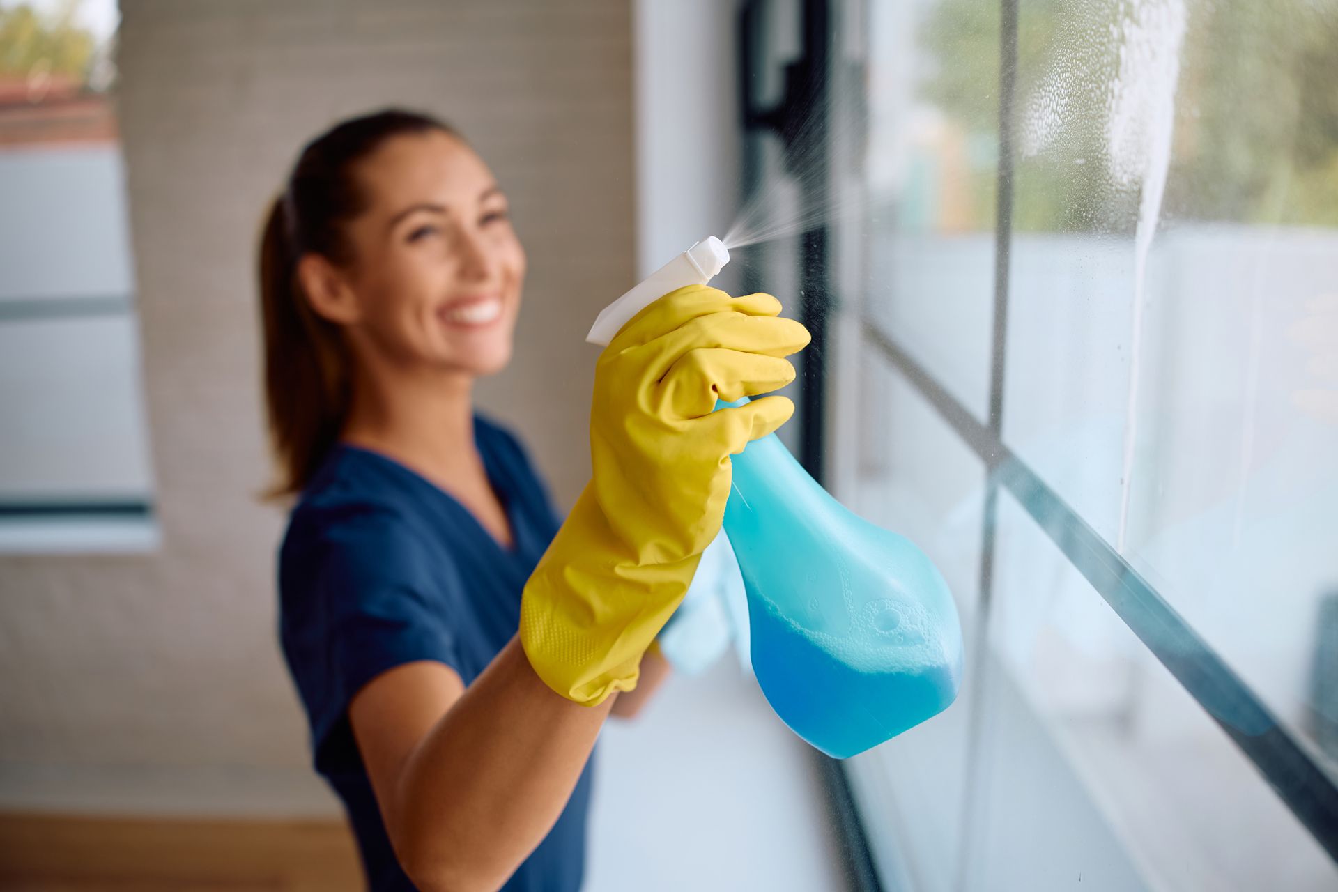 A cleaner spraying windows with detergent and providing commercial cleaning services. A cleaner spraying windows with detergent and providing commercial cleaning services.