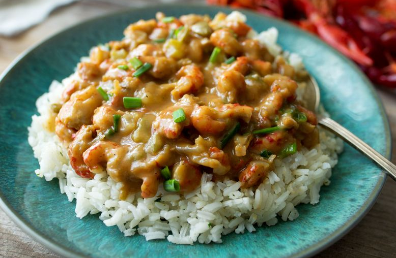 Crawfish étouffée served over rice on a turquoise plate.