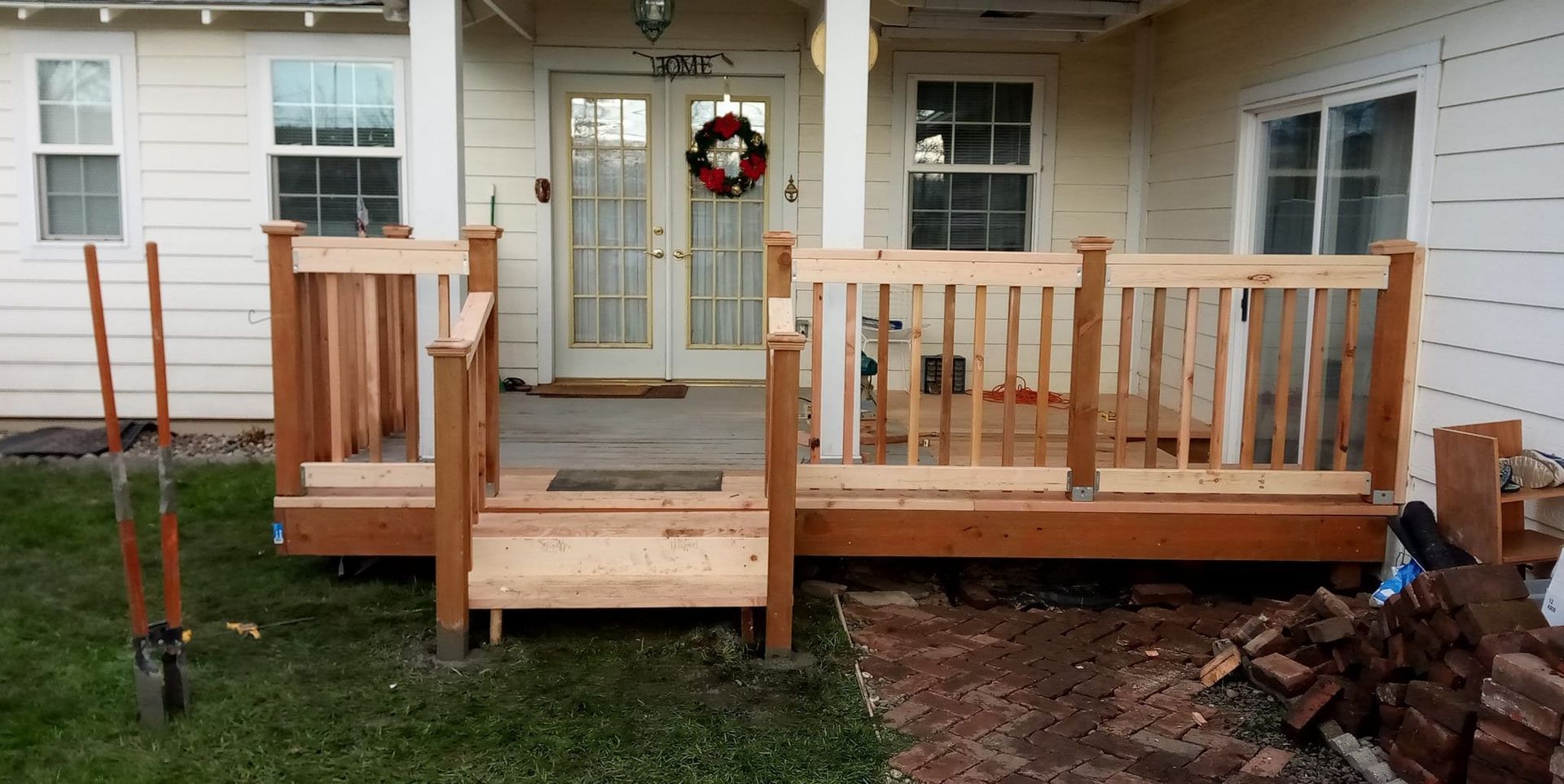 A partially built wooden deck with a set of stairs leading to a doorway. Tools are next to the deck.