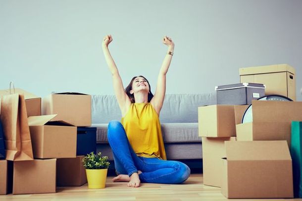 a woman is sitting on the floor in a living room surrounded by cardboard boxes