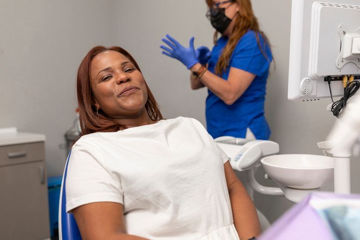 A woman is smiling while sitting in a dental chair.