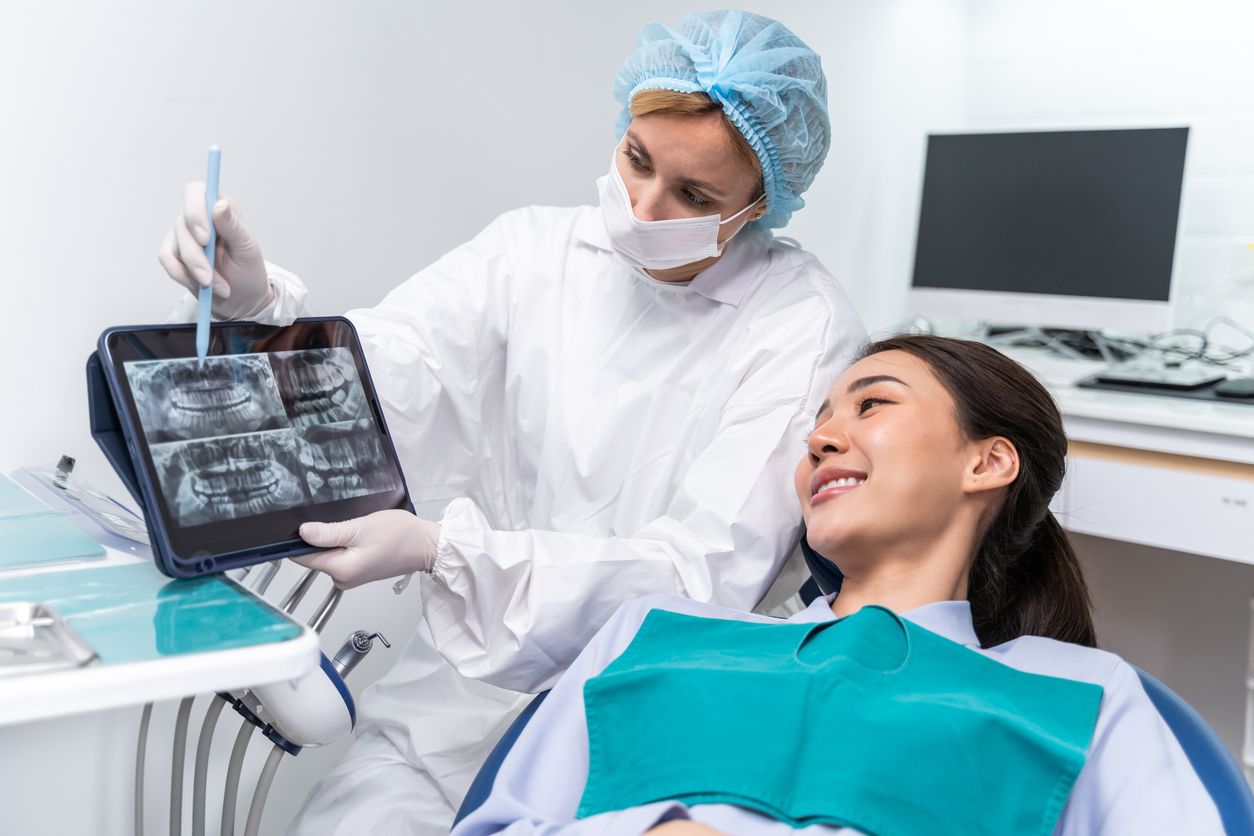 A dentist is looking at an x-ray of a patient 's teeth.