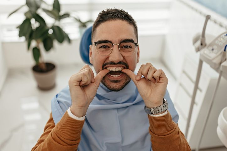 A man is sitting in a dental chair looking at his teeth.