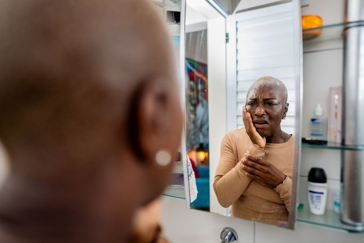 A woman is holding her face in pain because of a toothache.