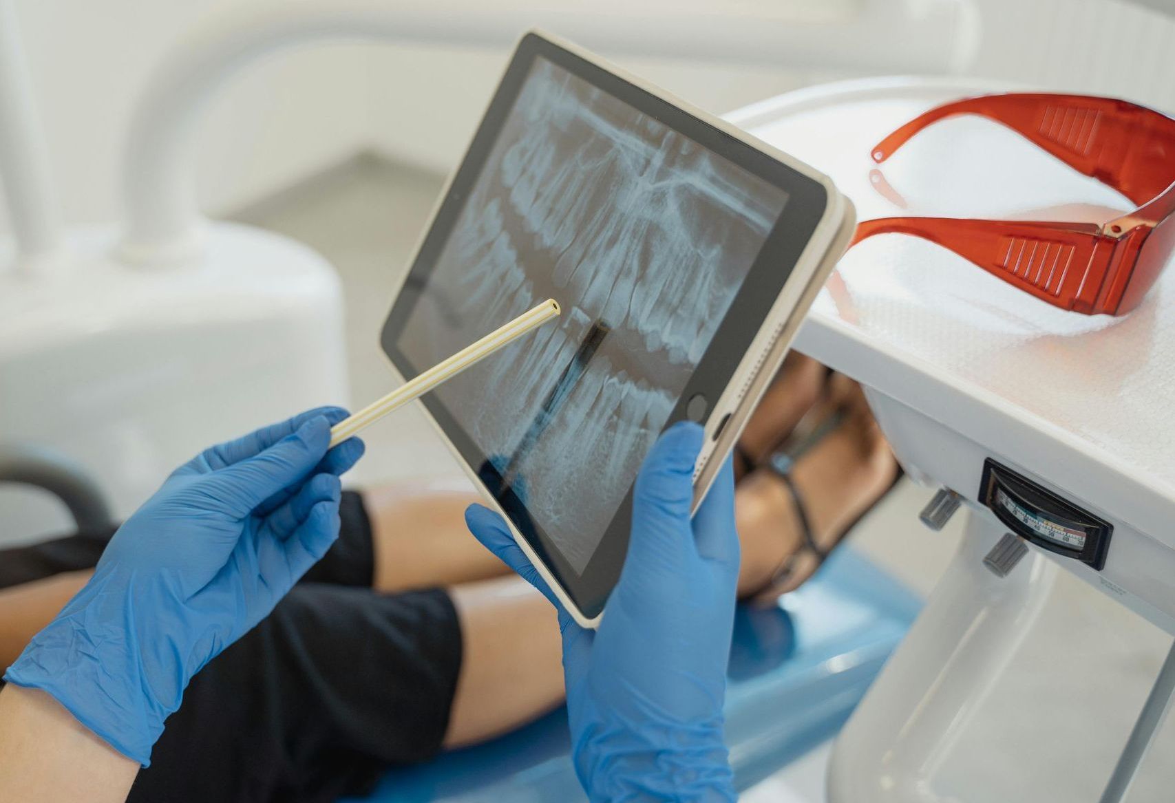 A dentist is looking at an x-ray of a patient 's teeth on a tablet.