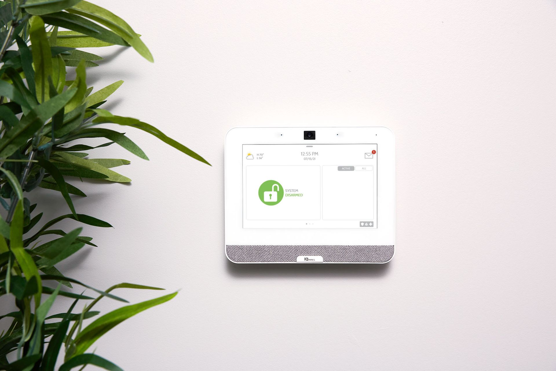 A smart device is sitting on a wall next to a plant.