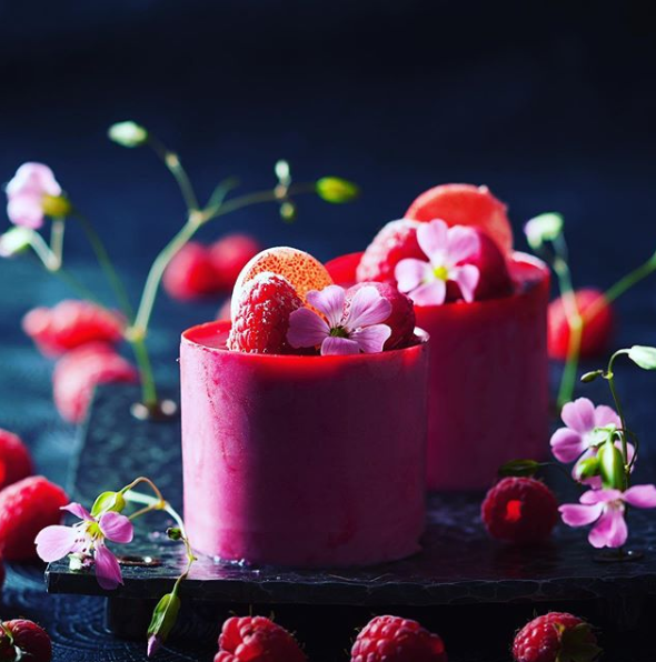 Eine Nahaufnahme eines Desserts mit Erdbeeren und Blumen auf einem Tisch.