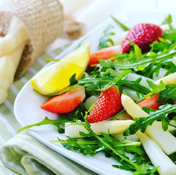 Ein Salat mit Erdbeeren und Spargel auf einem weißen Teller