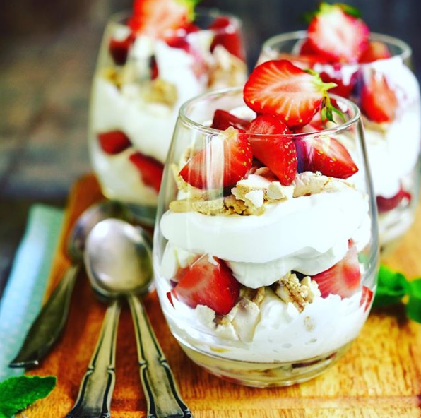 Ein Glas gefüllt mit Erdbeeren und Schlagsahne