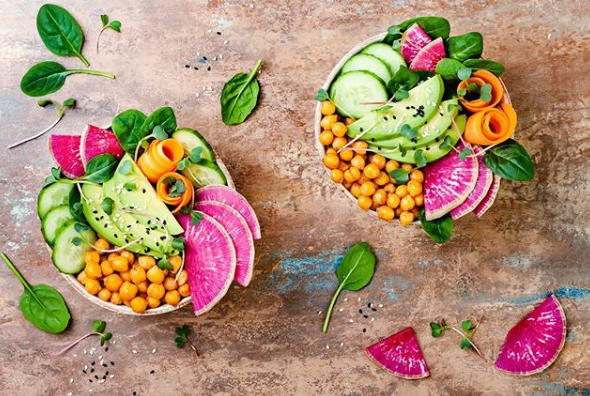 Zwei Schüsseln mit Gemüse und Kichererbsen auf einem Tisch.