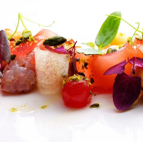 Eine Nahaufnahme eines Tellers mit Essen mit Tomaten und violetten Blättern