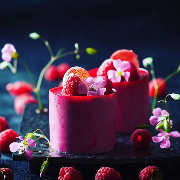 Zwei rosa Tassen gefüllt mit Erdbeeren und Himbeeren