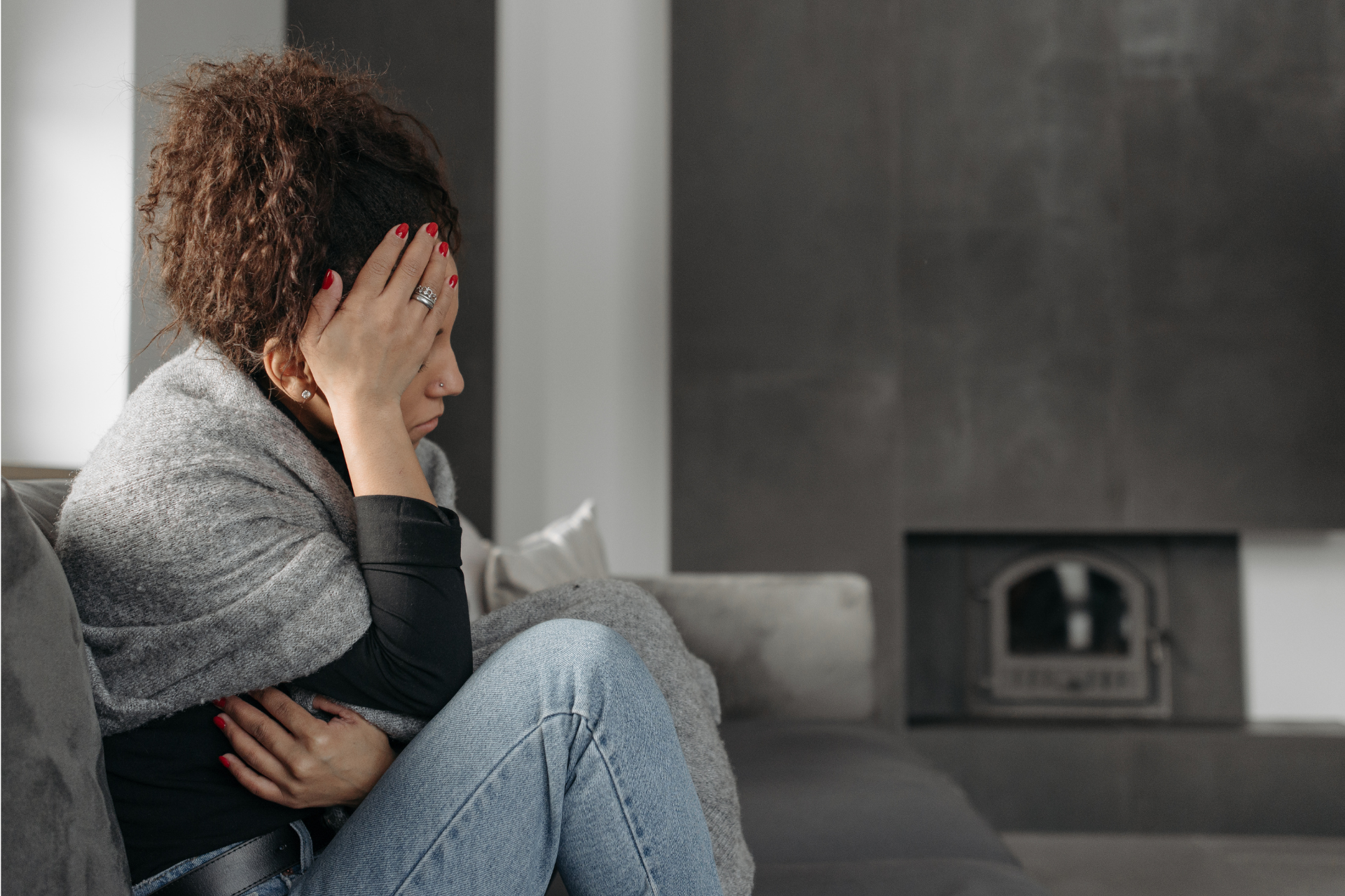 A woman is sitting on a couch with her head in her hands.