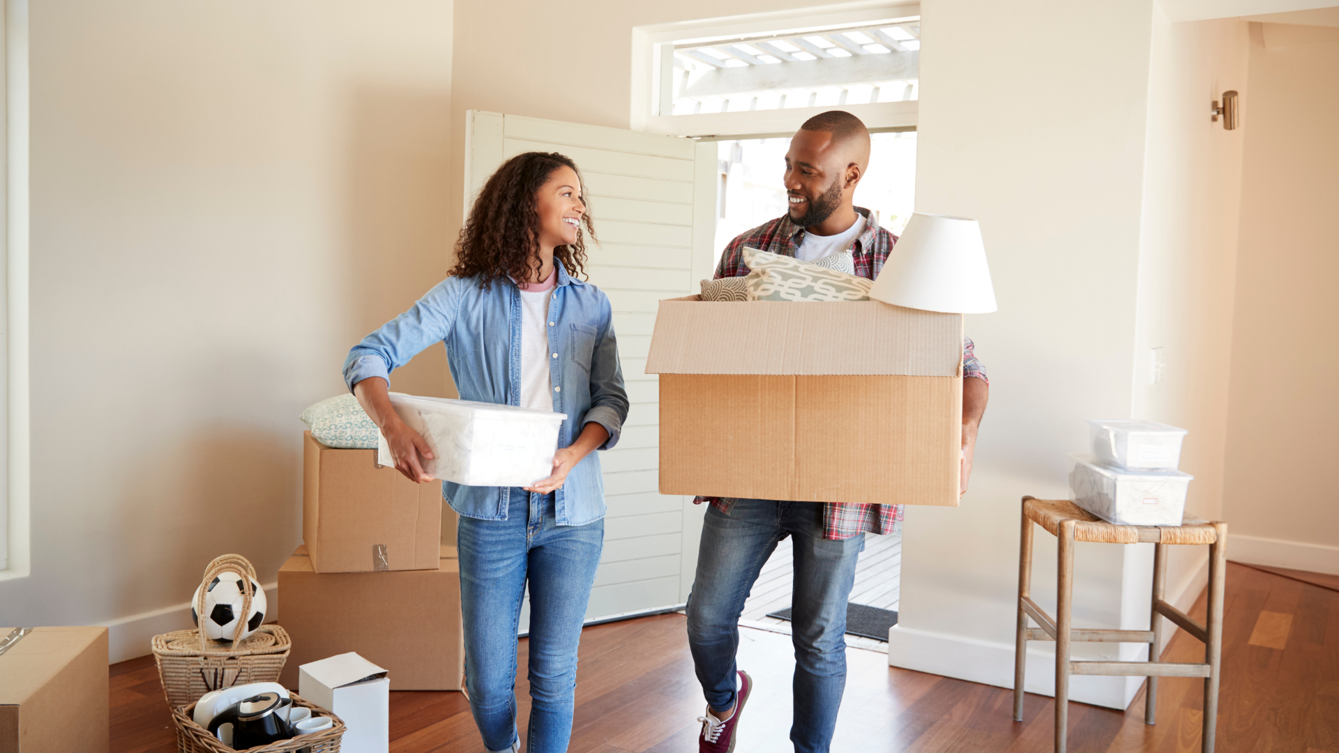 A man and a woman are carrying boxes into a new home.