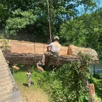 Person on a log raft; wooded setting. The person is working on it.