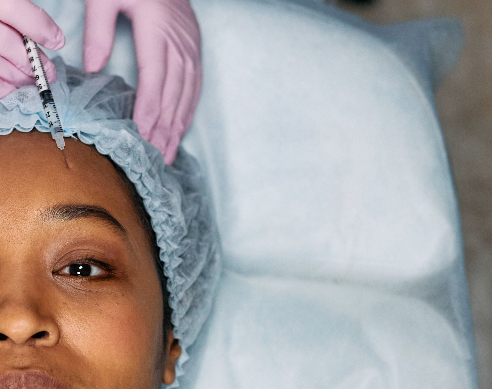 A woman is getting a botox injection in her forehead.