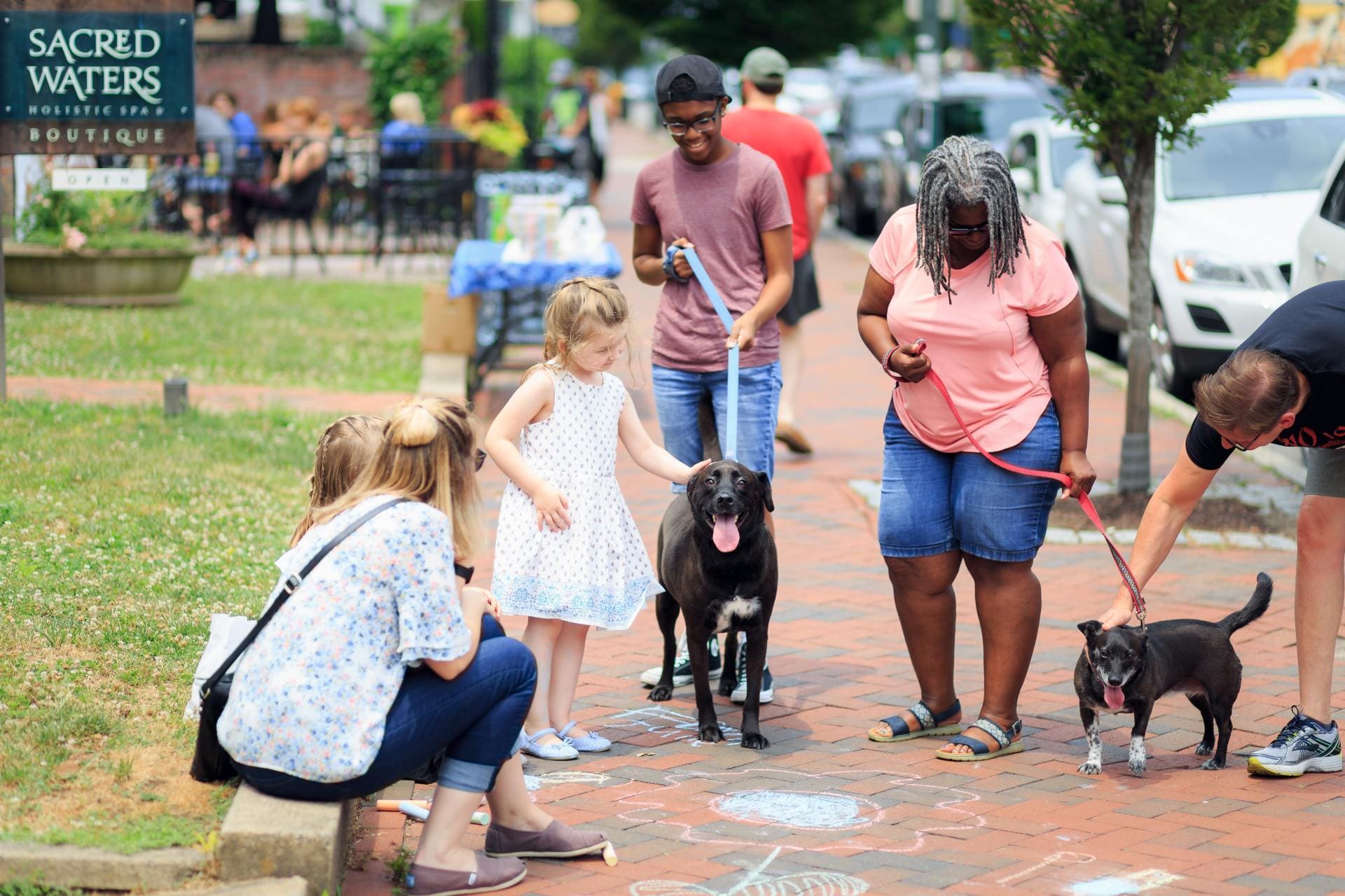 Kids petting dogs on the sidewalk