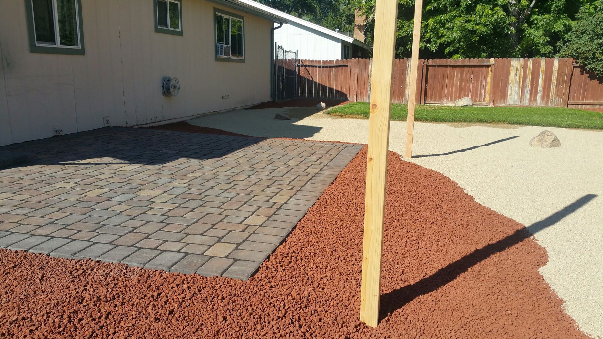 A brick patio with red mulch and a wooden post