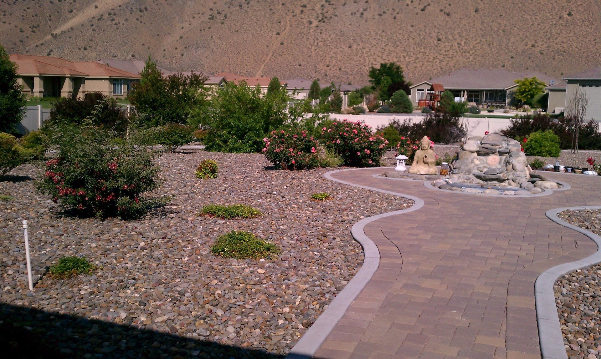 A brick walkway leading to a house with mountains in the background