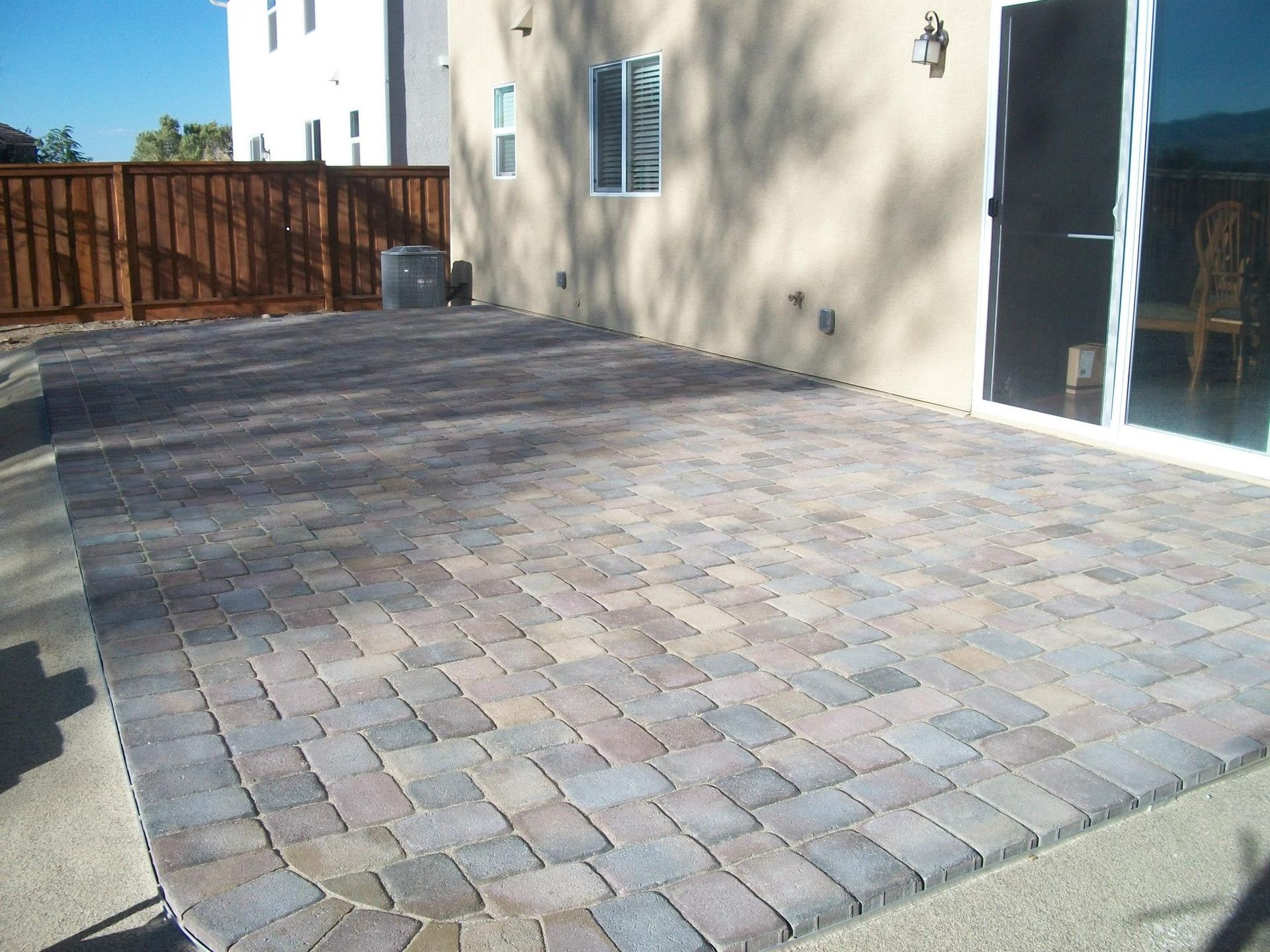 A patio with a sliding glass door and a wooden fence