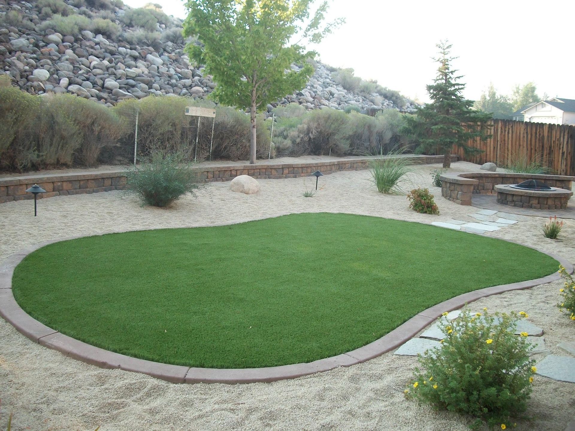 A lush green lawn with a fire pit in the background